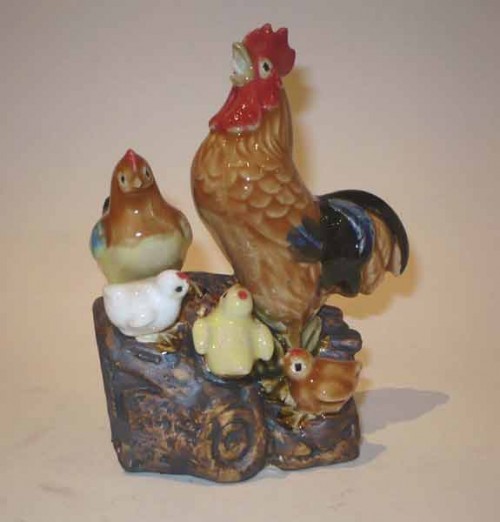 Une famille de poule et poussins en porcelaine sur un rocher.